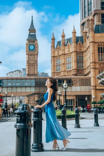 美丽的年轻女子穿着蓝色连衣裙站在城市的街道上