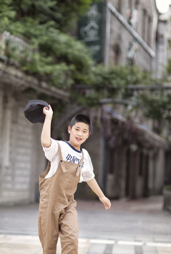 一个小男孩戴着黑色帽子站在街上