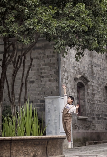 一个站在街边建筑物旁的年轻男子带着伞