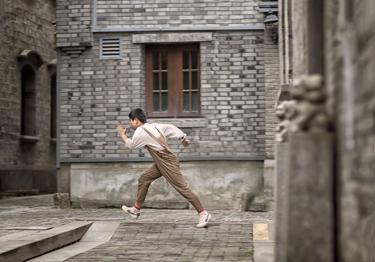 一名年轻人跑过一栋老建筑前的人行道