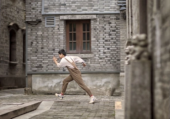 一名年轻人跑过一栋老建筑前的人行道