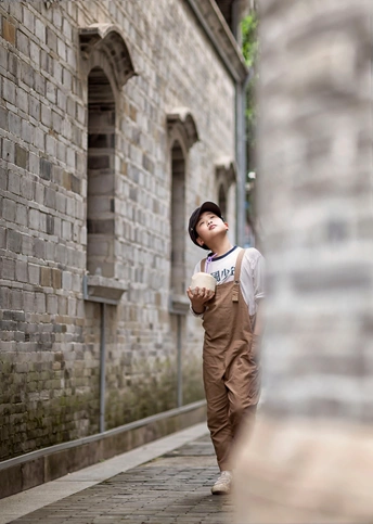 一个年轻男子和一个年轻女子沿着有砖墙一侧的巷子走 街边站着一个年轻男孩。