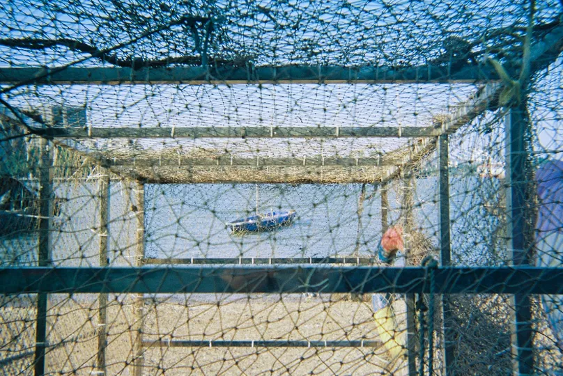 一个小船在水边 后面有围栏。