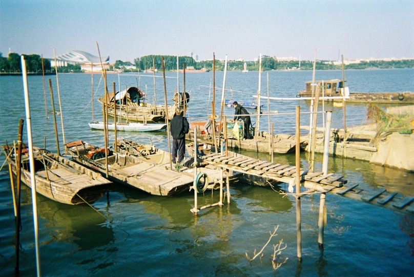 一个人站在一个木码头上 附近停着几艘小船。