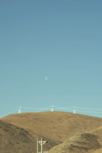 一辆飞越山丘、电线和天空中的月亮的火车。