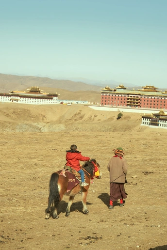 几个人在一个泥泞的场地上骑马 前景有一个男孩在走。