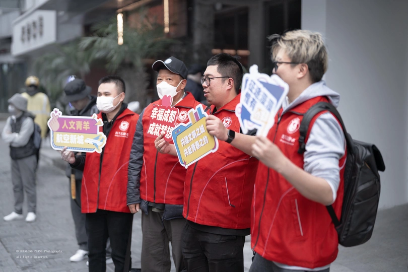 一些人穿着红衬衫和戴着口罩站在人行道上排队。