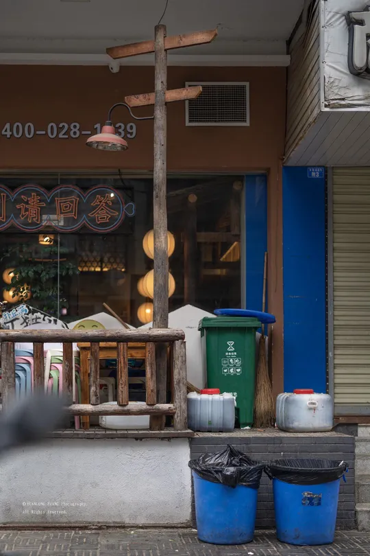 一个男子走在人行道上 商店前 一个男子坐在商店前的桌子旁。