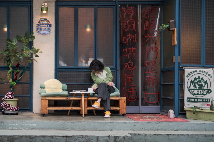 一个人坐在建筑物前面的长凳上