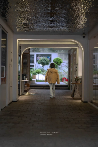 一个穿黄外套的女孩在夜晚走过一条走廊