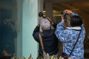 一个人站在一位正在拍照的女人旁边拿着相机