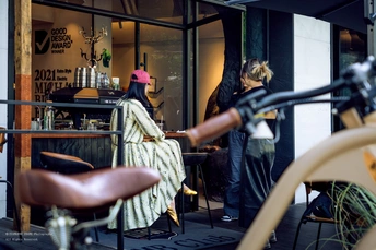 餐厅的外部视角 一位女士坐在桌子旁 一辆自行车停在窗户外。