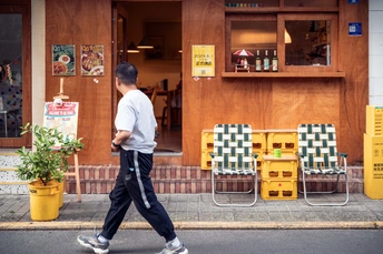一个年轻人走在街上 前面有滑板店。