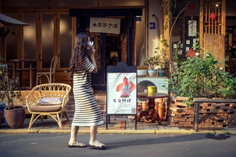 一位穿条纹裙子的女人站在人行道上 正在给商店打电话