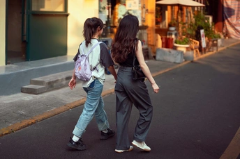 一对年轻人在人行道旁边走下街道 背着书包。