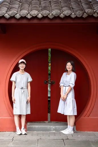 一些穿裙子的女人站在一栋红楼前面