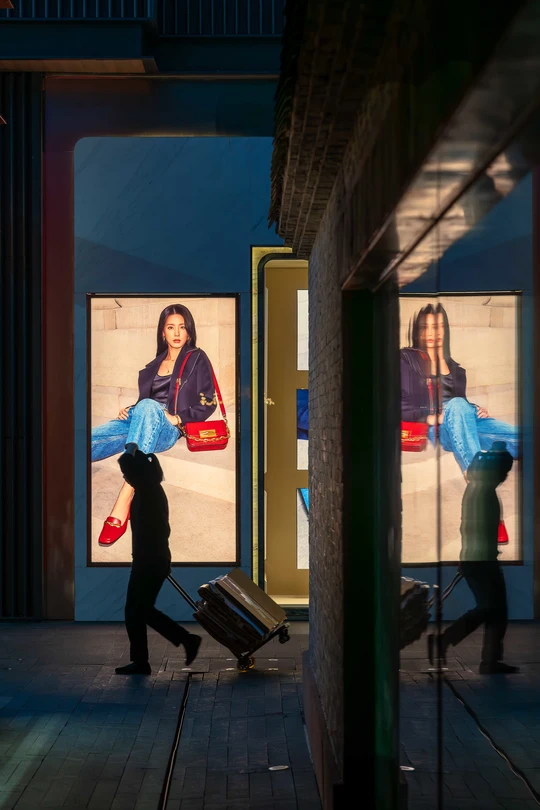 一个人拿着一个手提箱 一个人正在沿着建筑旁边的人行道走