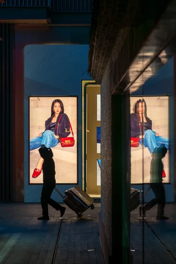 一个人拿着一个手提箱 一个人正在沿着建筑旁边的人行道走
