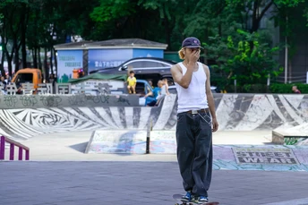 一个年轻人在滑板公园骑滑板 一个女子站在他身后。