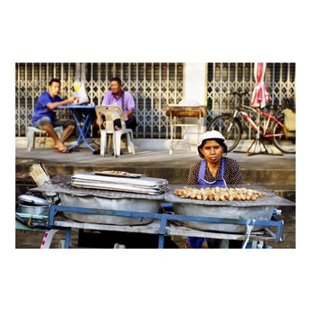 一位妇女坐在街边桌子旁售卖食物