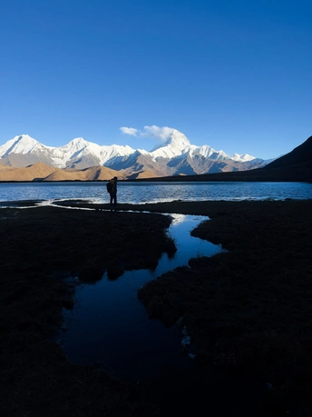 站在湖边的男人 背景是山脉。