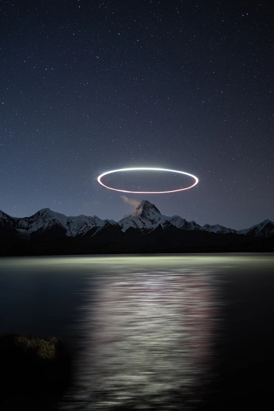 夜幕降临 湖边山峦上空出现一个光环。