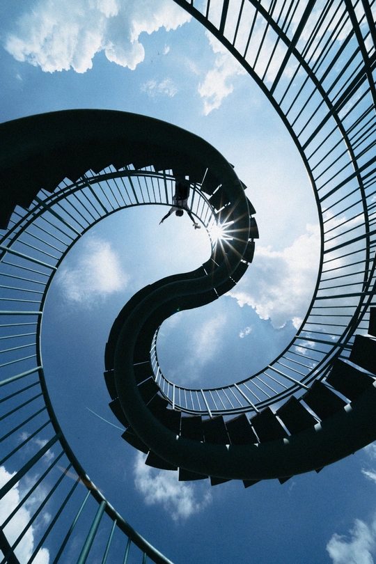 螺旋楼梯对着蓝天和多云的太阳