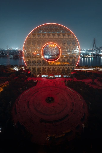 夜晚照亮的大型法拉第轮背景是一座城市。