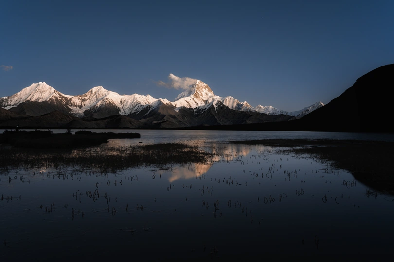 夕阳下 湖面上映照着一座山脉。