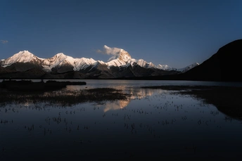 夕阳下 湖面上映照着一座山脉。