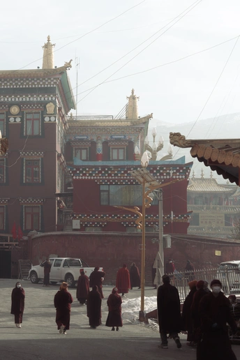 人们走在一条街道上 背景是有一栋红色的建筑。