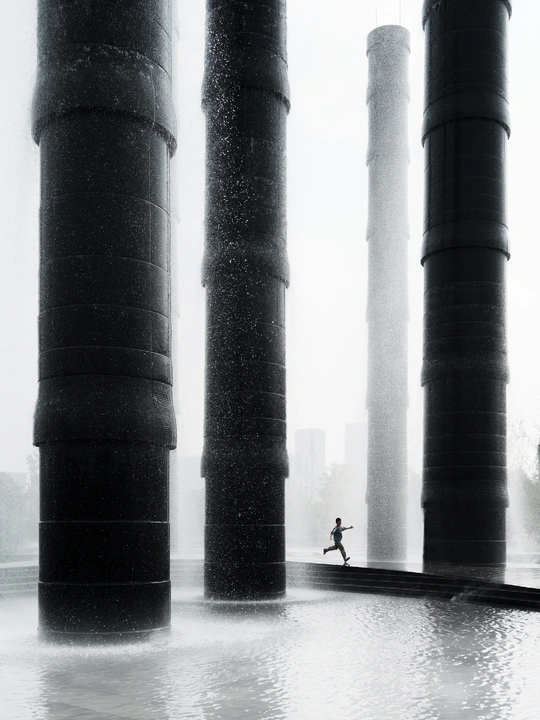 一张黑白照片 一个男子在雨中跑着 手里拿着伞 一个女子在水中跑着。