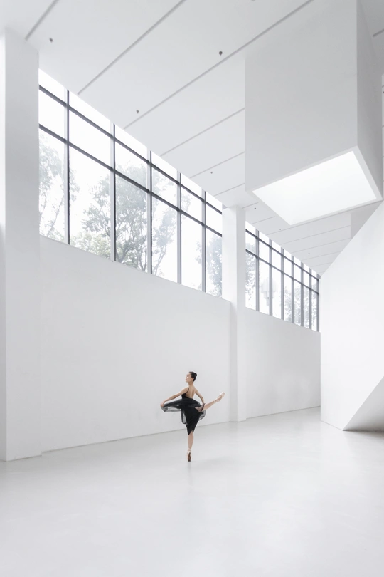 一个穿着黑白衣服的年轻女子在空荡荡的房间里跳舞 窗外有巨大的窗户。