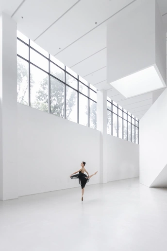 一个穿着黑白衣服的年轻女子在空荡荡的房间里跳舞 窗外有巨大的窗户。