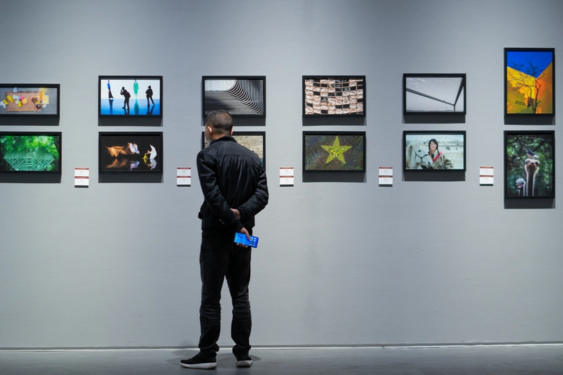 一个男子站在艺术画廊里 正在看墙上的画。