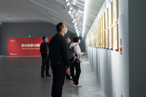 一个戴面具的人在走一条走廊 人们正在看墙上的艺术作品。