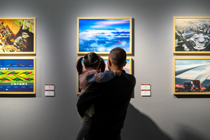 一个男子和一个女子抱着一个孩子 在艺术画廊里看着墙上的画。