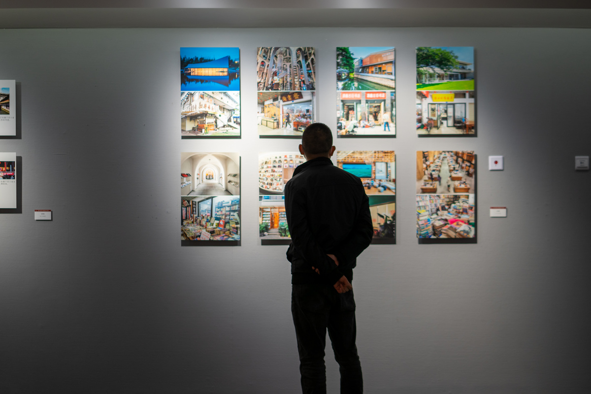 一个男子站在艺术画廊里 正在看墙上的画。