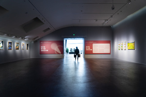 一个博物馆里的黑暗房间 墙上挂着画 人们四处走动。