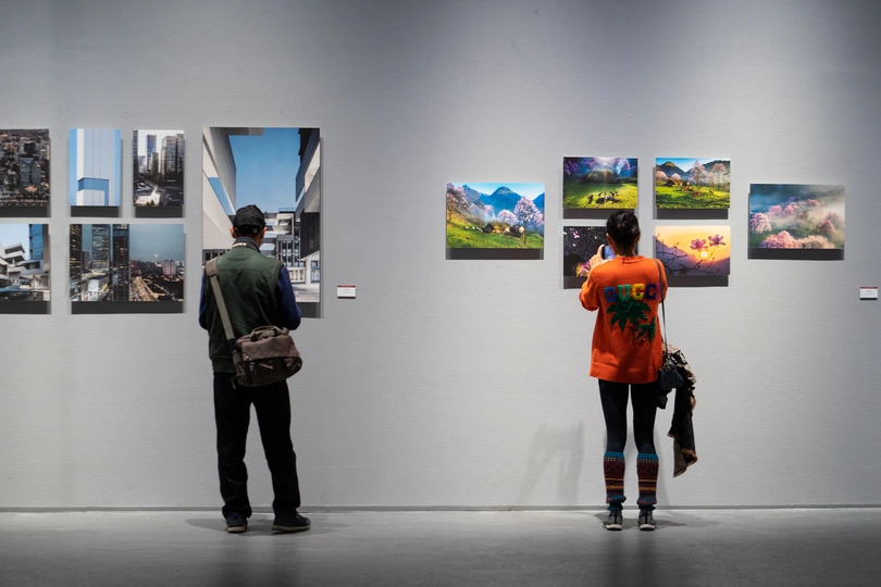 一个男性和一个女性站在艺术画廊里 注视着墙上的画。