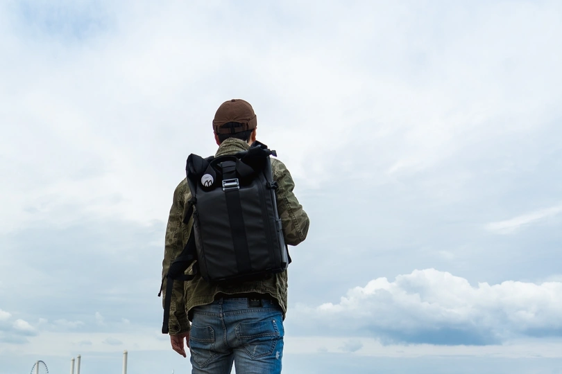 一个人背着背包站在码头上 眺望着大海。