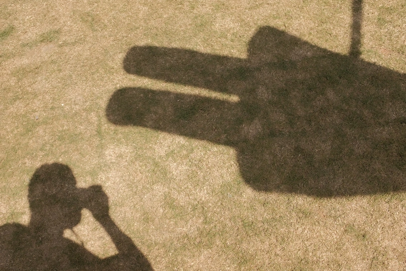 一个人站在草地上 手里拿着一把伞的阴影。