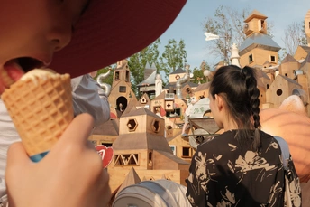 一个戴帽子的男人看着一个年轻女孩吃冰淇淋