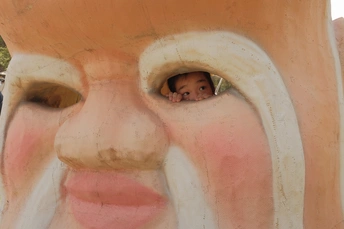 一个小孩子正透过一个有脸的大锅的窗口向外看。