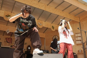 一个年轻人站在舞台上 手里拿着滑板 其他年轻人正在舞台上表演。