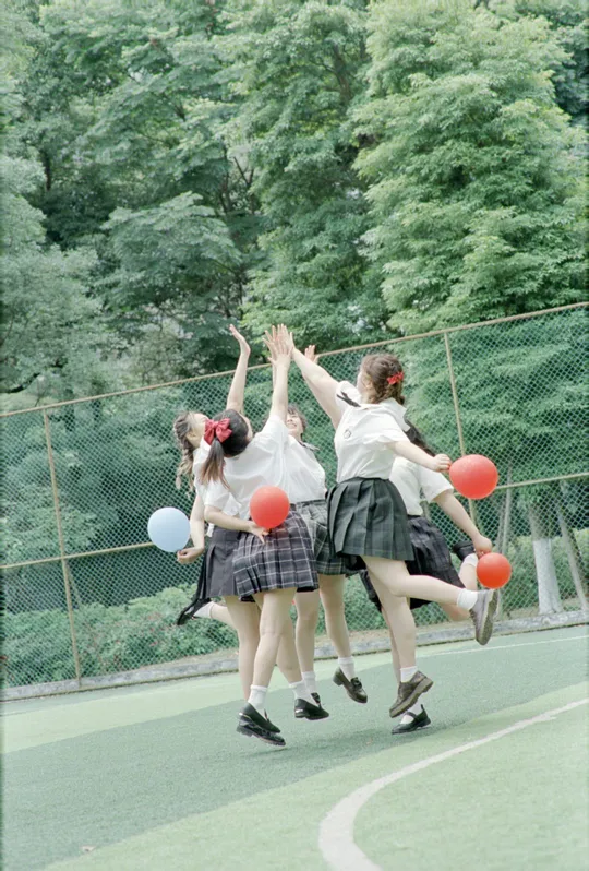 穿着校服的年轻女孩们在篮球场上打篮球。