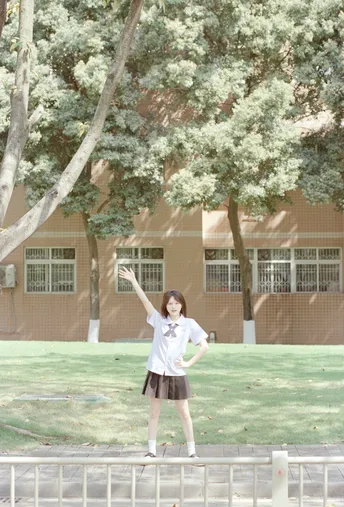 一个小女孩站在围栏前和树旁