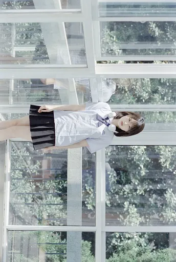 一位穿着白色连衣裙的年轻女子站在窗前