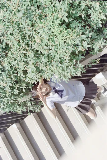 一位女士带着一只狗走下一些楼梯 狗站在一棵树旁边。