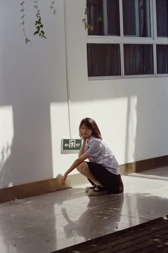 一个年轻女子坐在建筑物地板上 另一个人跪在附近。